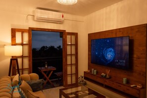 Relax in a spacious living room with a large flat-screen TV, comfortable seating area, and sliding door to an outdoor seating space.