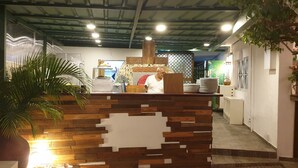 A reception area with a wooden counter, a large potted plant, and a tiled floor. - PLAYA BLANCA BED & BREAKFAST (San Rafael del Yuma)