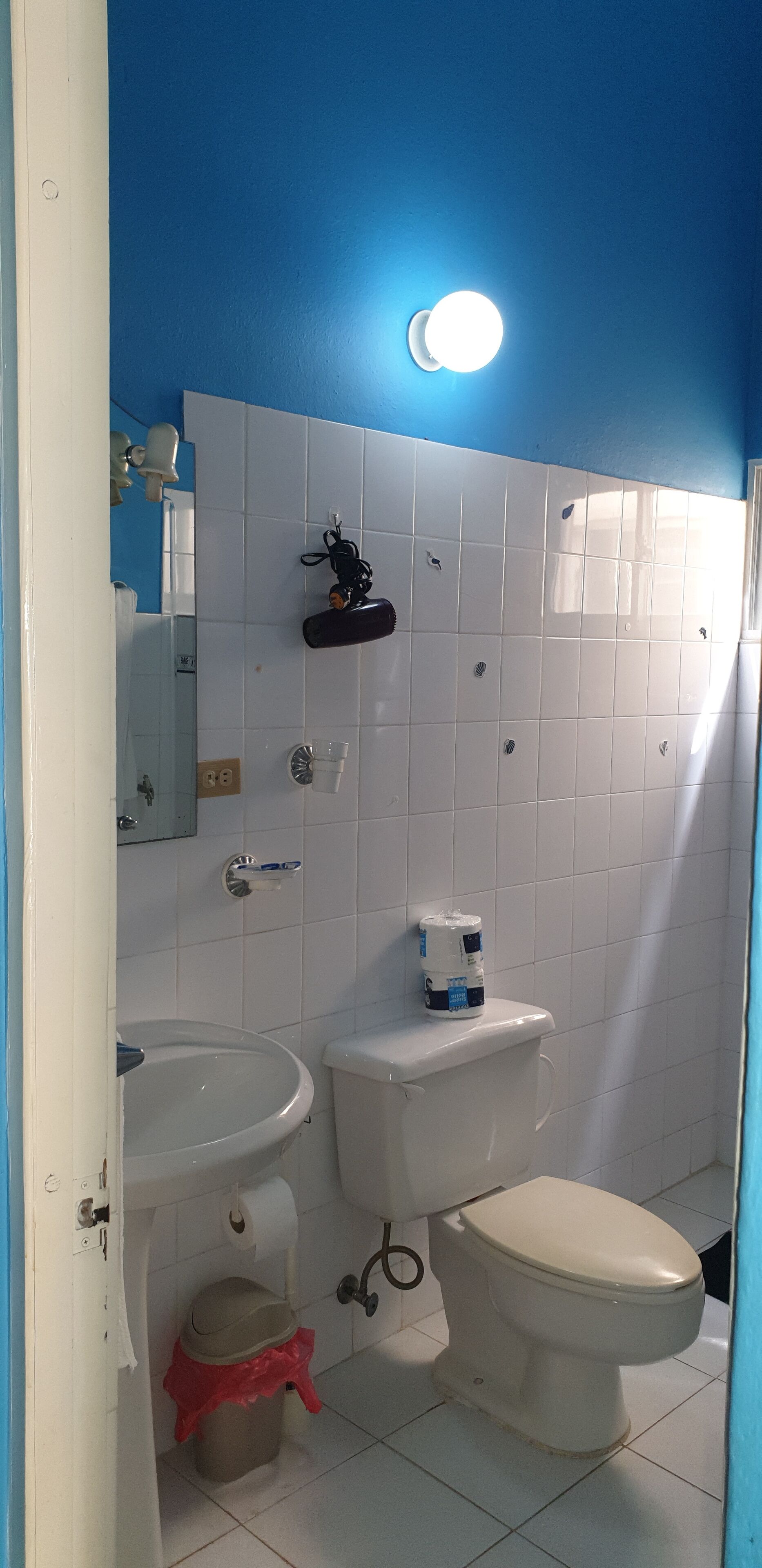A bathroom with a white sink, toilet, and bidet, a mirror, and a blue wall.