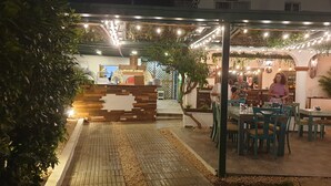 An outdoor dining area with tables and chairs, a counter, and a brick pathway. - PLAYA BLANCA BED & BREAKFAST (San Rafael del Yuma)