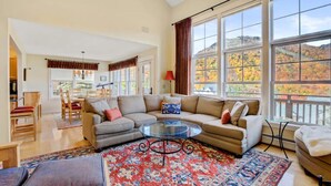 A spacious living room with a large window, a glass coffee table, and a cozy seating area.