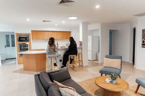 A modern kitchen with wooden cabinets, a central island, and a dining area with stools.
