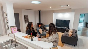 Una sala de estar moderna con sofá, televisor, zona de cocina con lavabo y chimenea.
