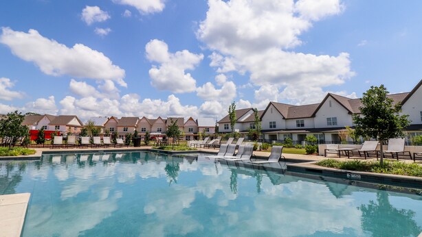 Una piscina con sillas de descanso, rodeada de edificios residenciales.