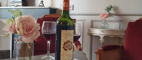 A room with a table displaying a wine bottle, glasses, and a vase with flowers.