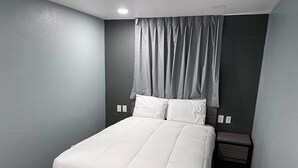 A neatly made bed with white bedding in a room with grey walls and a dark floor. - 2 Room Suite - Indoor Pool and Spa - Walk to the Boardwalk - No Cleaning Fee! (Santa Cruz)