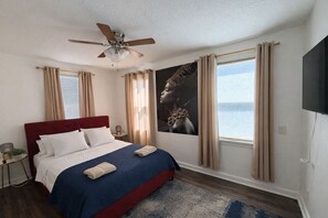A bedroom with a bed, a ceiling fan, a TV, and a window with curtains. - Sunny Riverside Stay • Near Dining • Sleeps 6 (Jacksonville)