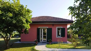 A small pink house with green shutters, a tiled roof, and a paved front yard. - La Casina (Barga)