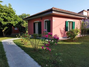 A pink house with green shutters, a paved driveway, and a garden with pink flowers. - La Casina (Barga)