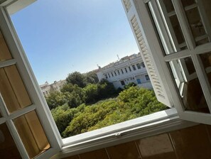 A window with a view of a building and greenery.
