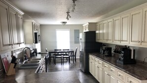 Eine Küche mit weißen Schränken, einer Granitarbeitsplatte, einem Kühlschrank und einer Kaffeemaschine.