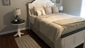 Ein ordentlich eingerichtetes Schlafzimmer mit Bett, Nachttischen und Wandbildern.