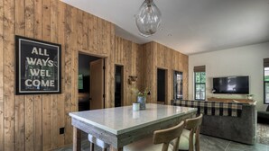 Ein modernes Interieur mit einer Holzwand, einem Esstisch mit Stühlen, einer Couch und einem Fernseher.