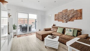 A modern living room with a sectional sofa, a coffee table, and a large window. - 1 Bedroom Condo in Goslar (Goslar)