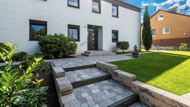 A modern two-story house with a white exterior, a front door, and a small front yard with steps leading to the door. - 1 Bedroom Condo in Goslar (Goslar)