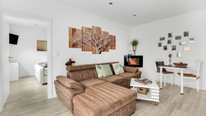 A modern living room with a sectional sofa, a dining table with chairs, and a fireplace. - 1 Bedroom Condo in Goslar (Goslar)