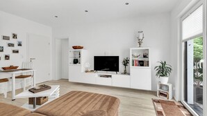 A modern living room with a sofa, TV, and white cabinetry. - 1 Bedroom Condo in Goslar (Goslar)