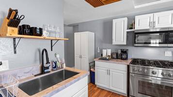Una cocina moderna con pileta, estufa y alacenas blancas.