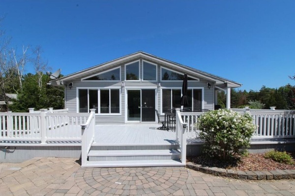 Wall of windows, vinyl deck and stone patio at backyard on a sunny day.