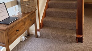 A staircase with a patterned carpet, a wooden desk with a globe, and a sign for a guest house. - Broadhaven Road (Wick)