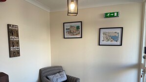 A cozy room with a chair, a wall-mounted light fixture, and two framed pictures. - Broadhaven Road (Wick)