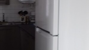 Une cuisine avec un réfrigérateur blanc, un four à micro-ondes et un évier.