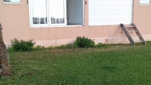 Un bâtiment doté d’un toit plat, d’une cour gazonnée et d’une échelle menant à une porte.