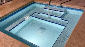 Ein rechteckiger Pool mit klarem, blauem Wasser, umgeben von einem strukturierten, braunen Boden.