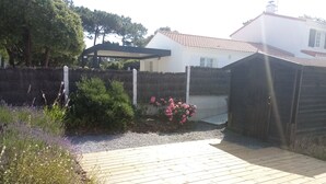 Une terrasse en bois avec un chemin de gravier menant à une maison dotée d’un porche abrité.