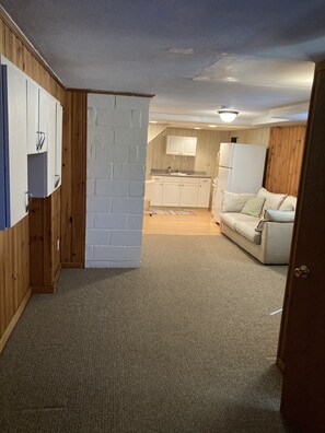 Cozy living space with a kitchenette, seating area, and warm wooden paneling.