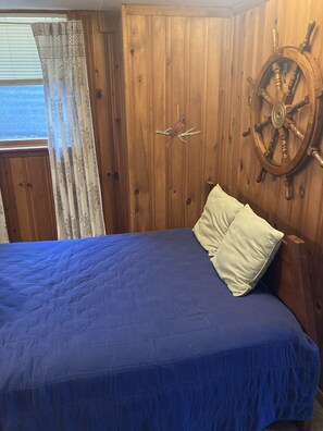 Cozy retreat with a ship's wheel, comfortable bed, and natural light.