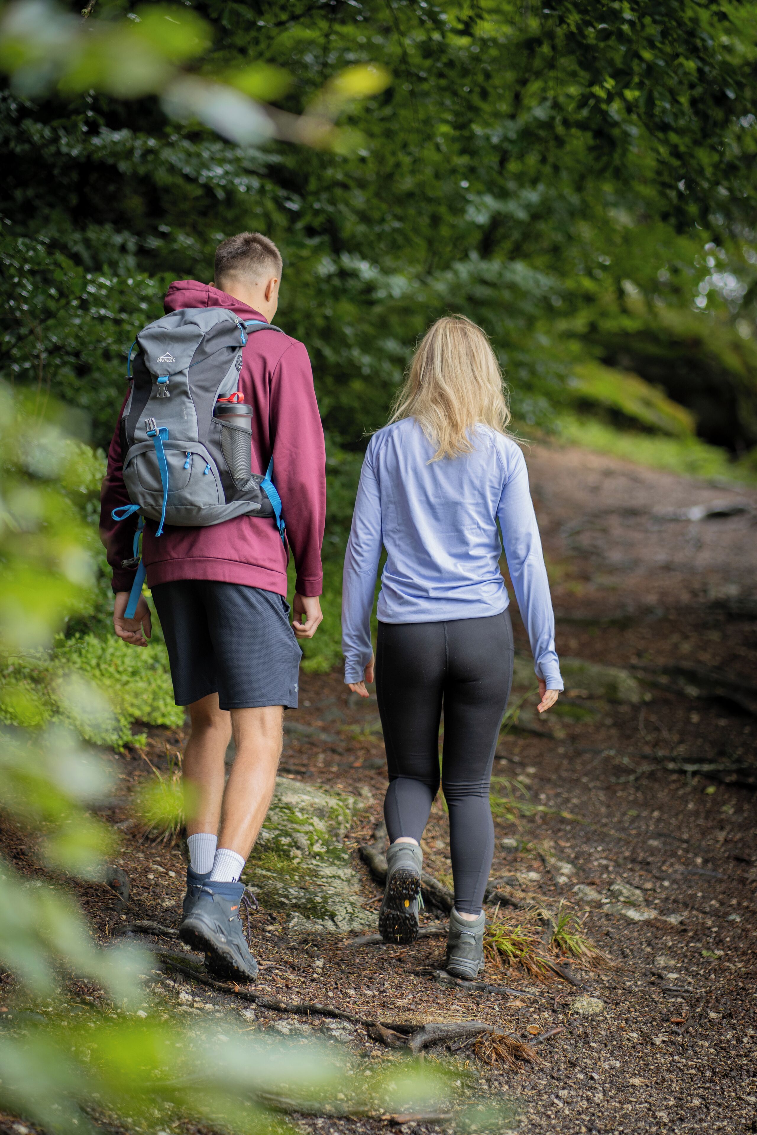 Two people walking on a forest trail.