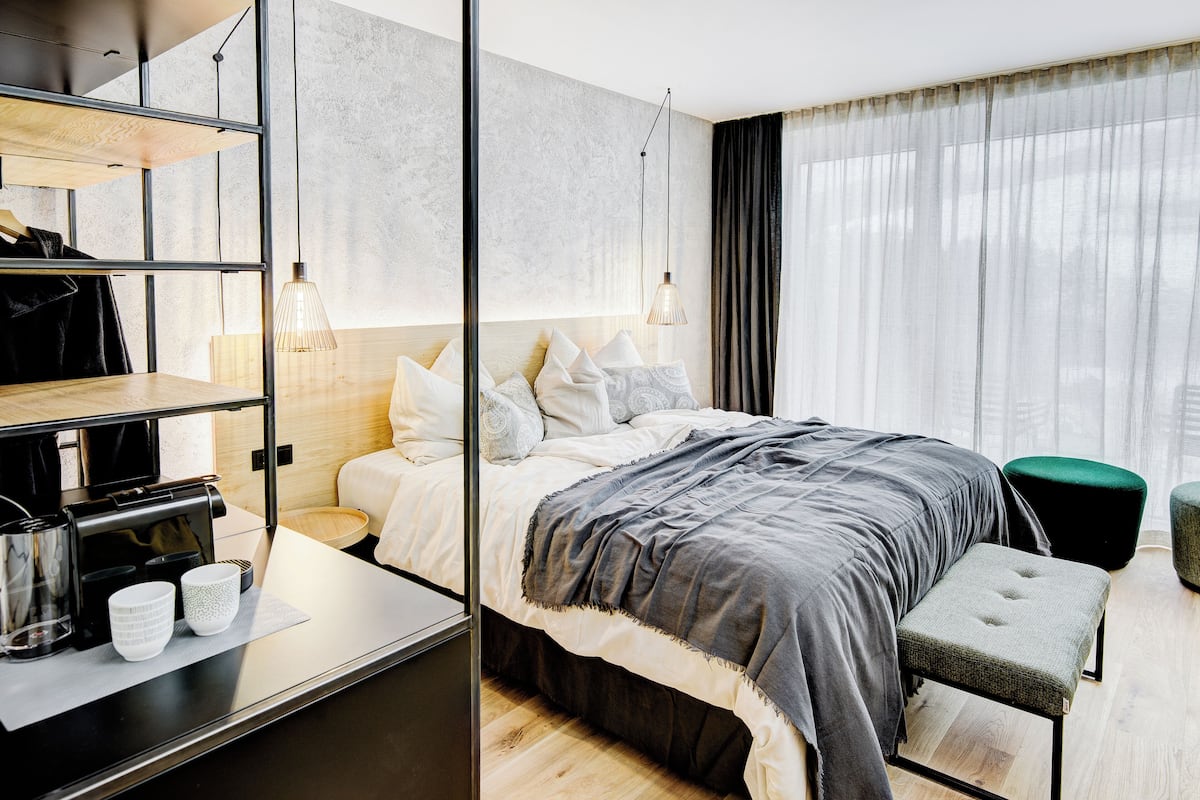 A modern hotel room with a bed, bedside table, and a coffee machine.