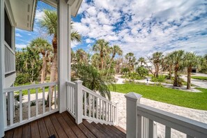 A wooden porch with white railings overlooking a landscaped garden with palm trees and a clear sky. - Sanibel Home ready for rentals ! (Sanibel)