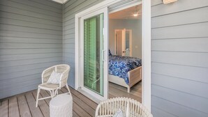 A room with a bed, a chair, and a sliding glass door leading to another room. - Sanibel Home ready for rentals ! (Sanibel)