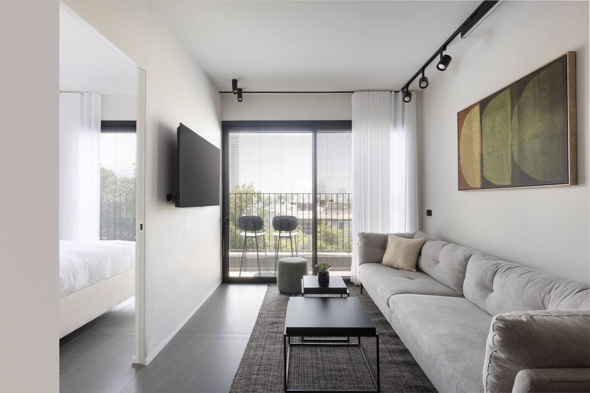 A modern living room with a sofa, a coffee table, and a TV mounted on the wall.
