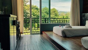 A bedroom with two beds, a view of greenery outside, and a balcony. - JALMIN Samui Hotel (Koh Samui)