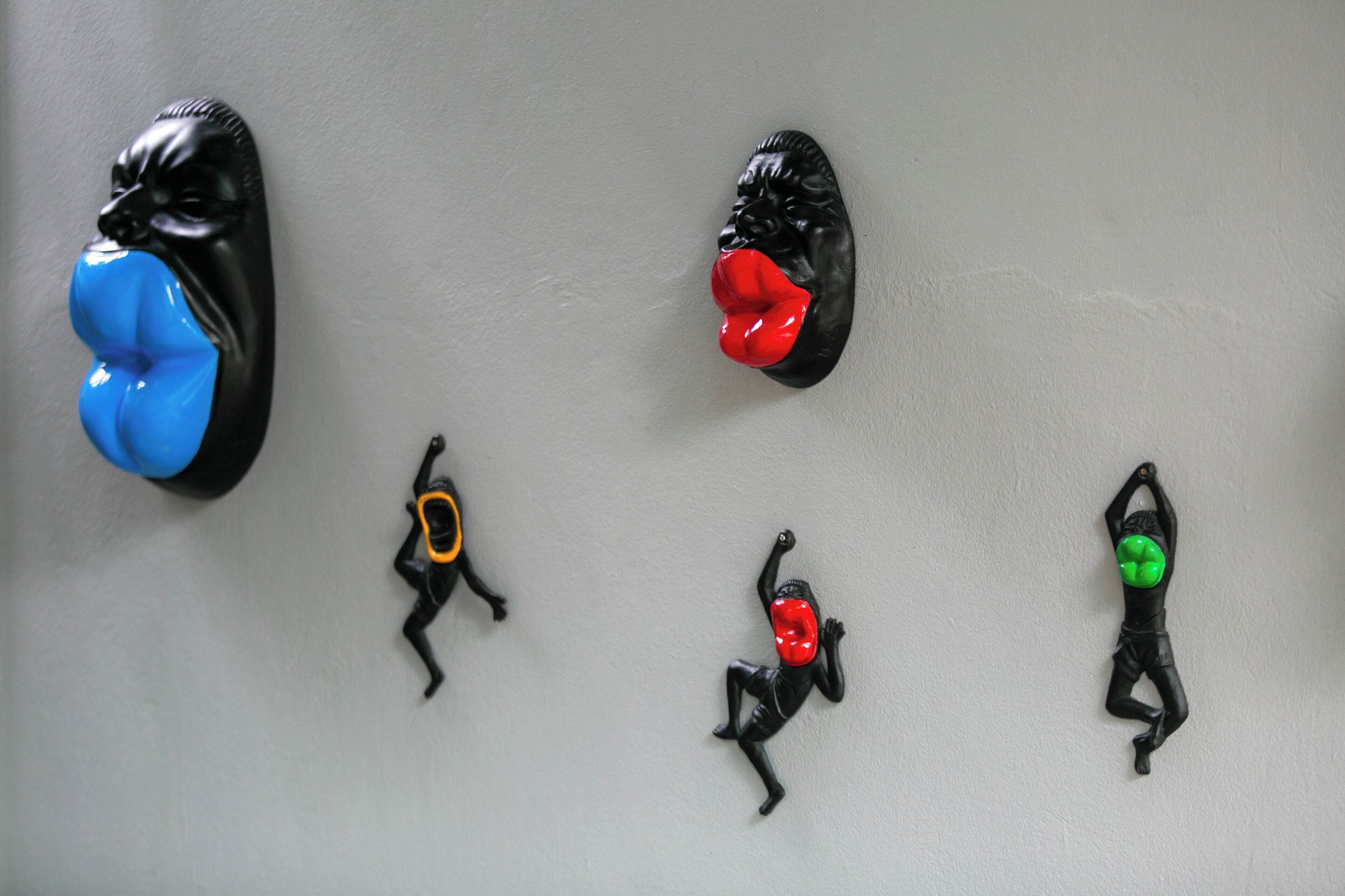 A wall with five black sculptures of human figures in various poses.