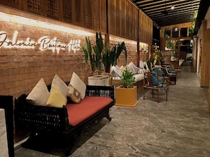 A lobby with a brick wall, a sofa with cushions, and a potted plant. - JALMIN Samui Hotel (Koh Samui)