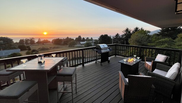 Terassi, jossa on ulkokalusteita, grilli ja upea näköala auringonlaskuun.