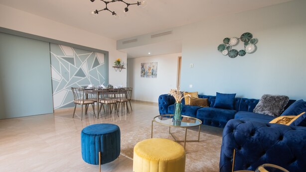 A modern living room with a blue sofa, a yellow ottoman, and a glass coffee table. - Blue Paradise,a ray of Sunshine Between sea & Pool (Sonaba, Agadir)
