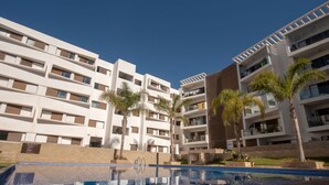 A modern hotel with multiple floors, a swimming pool, and palm trees. - Blue Paradise,a ray of Sunshine Between sea & Pool (Sonaba, Agadir)