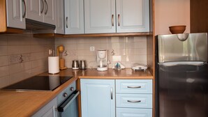 A kitchen with light blue cabinets, a stainless steel refrigerator, a coffee maker, and a stove. - PETRA Traditional HOUSE 2 (Ormos Korthiou)