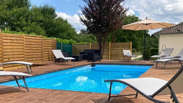 Eine Holzterrasse mit Pool, Liegestühlen und einem Holzzaun.