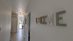 Ein Flur mit einem 'WELCOME'-Schild und einer Tür zu einem hellen Raum.