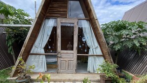 A triangular wooden house with a front door, windows, and a small porch area. - Nha cua Nep (Dien Hong)