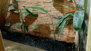 A room with a brick wall, a wooden floor, and a black gravel area. - Nha cua Nep (Dien Hong)