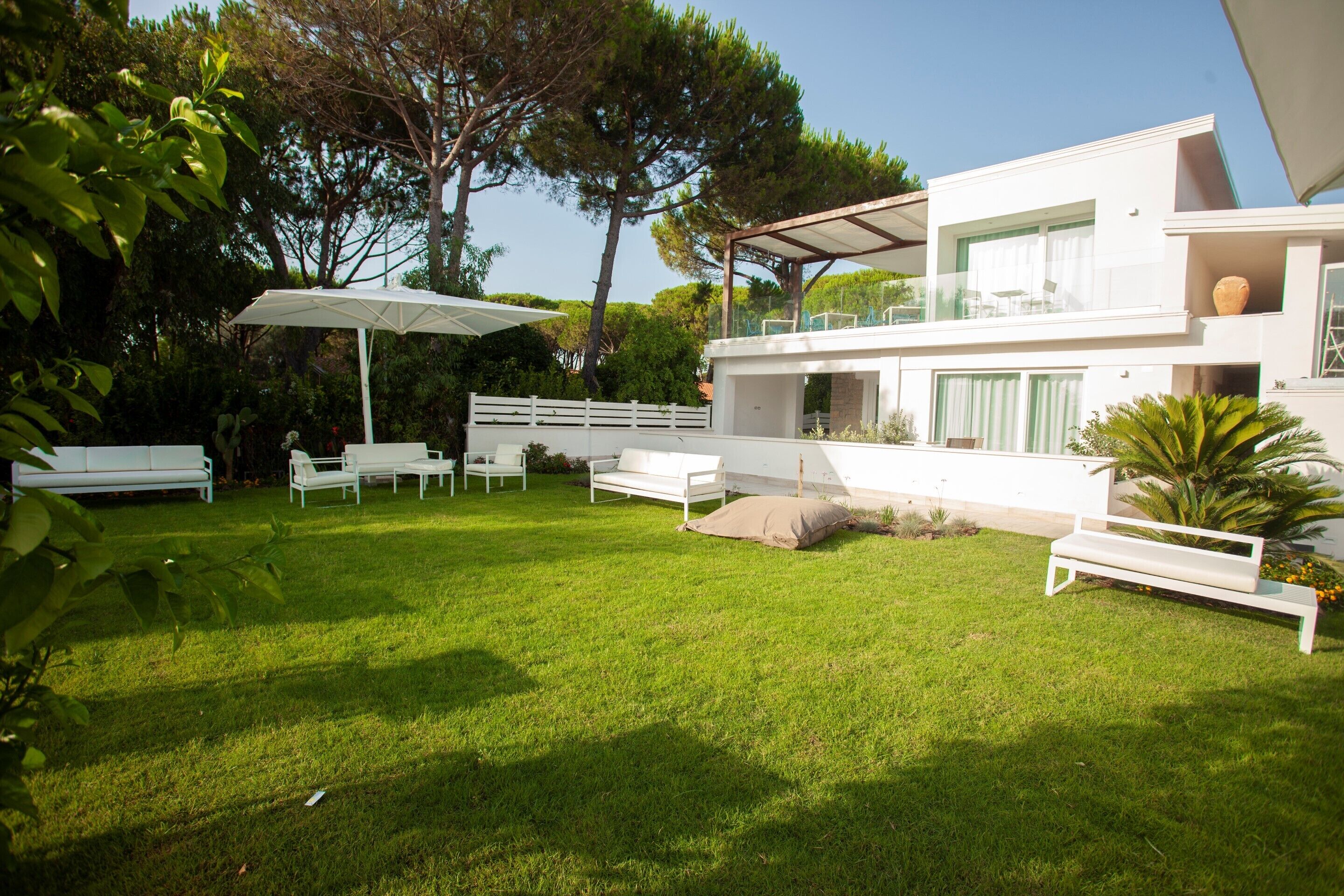 A modern house with a spacious backyard, white furniture, and a pergola.