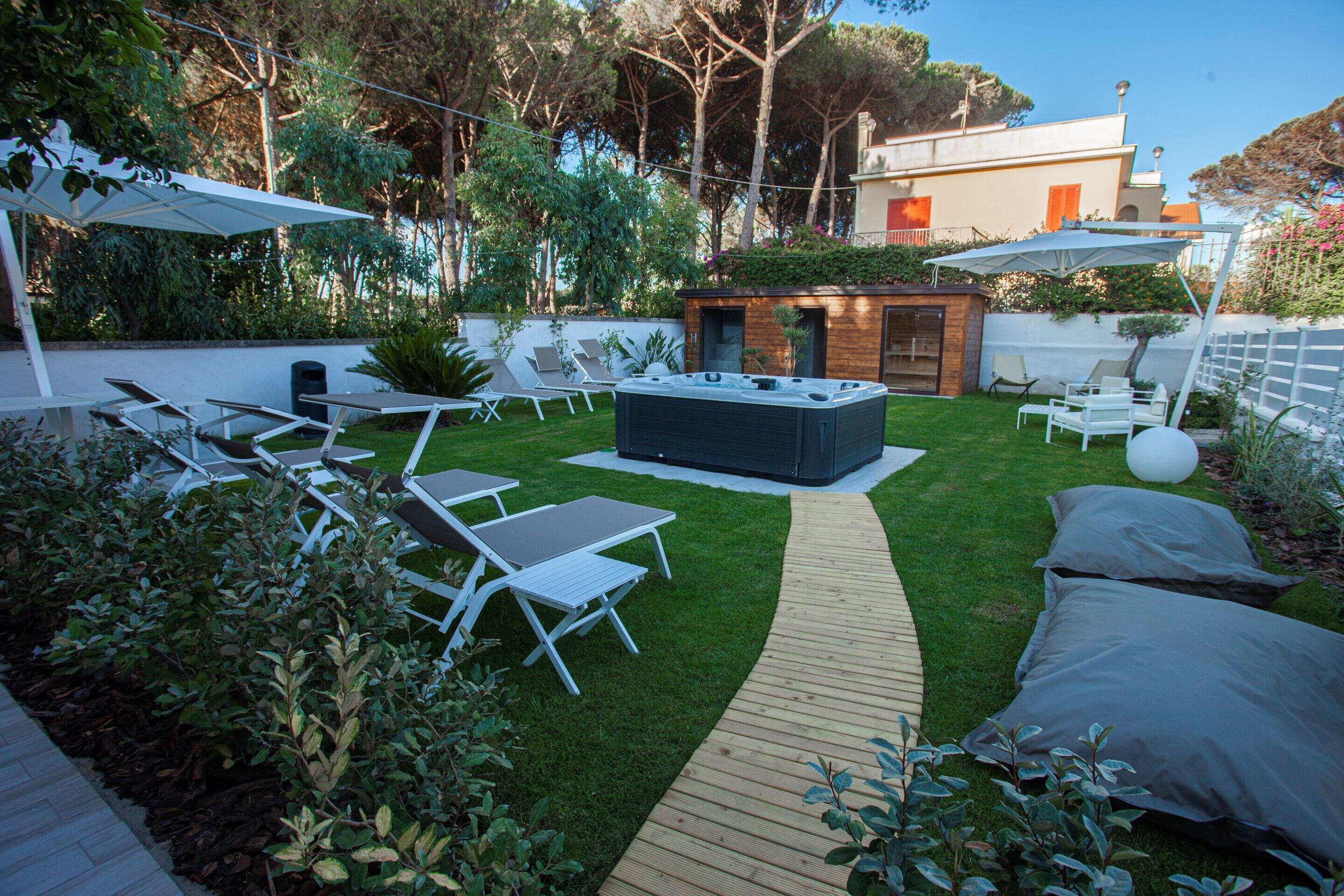 Un patio trasero con un jacuzzi, sillas de descanso y una terraza de madera.