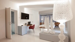 A modern hotel room with a flat-screen TV, a dining area, and a large decorative lamp.